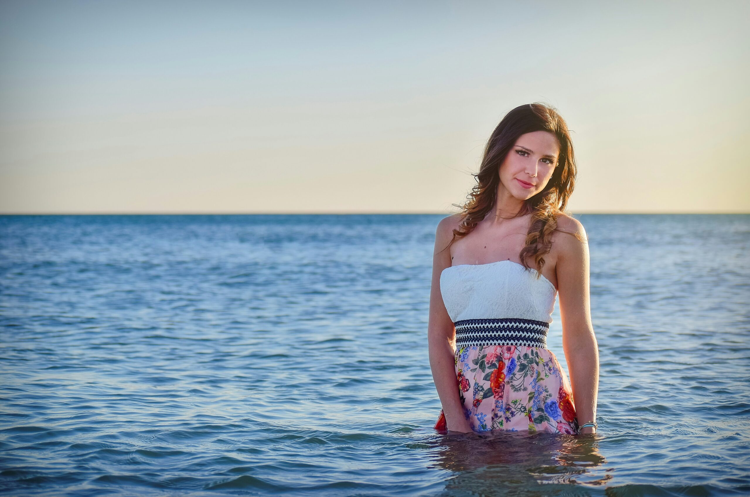 woman on ocean wearing dress talking photo during sunset