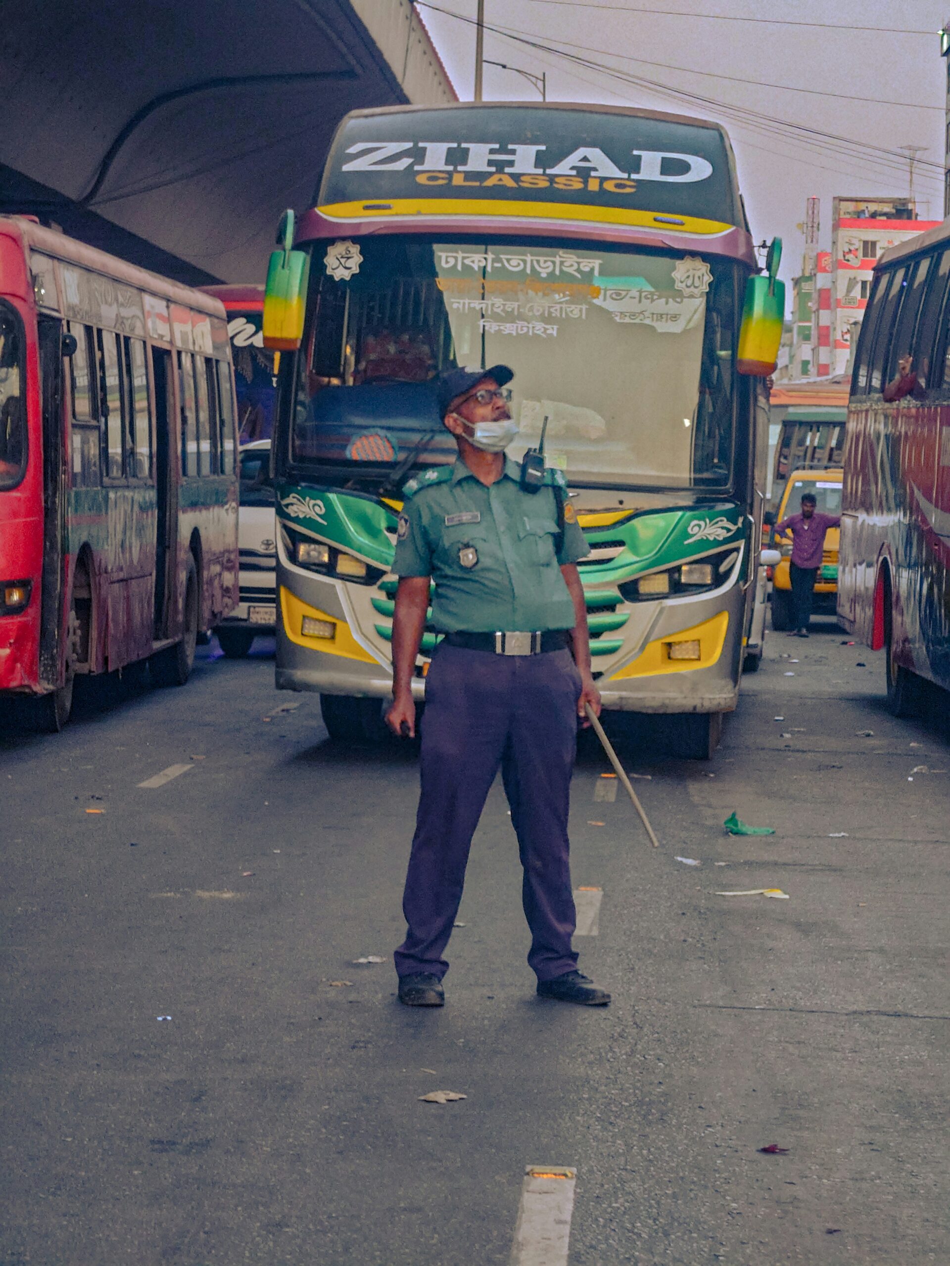 A man standing in the middle of a street next to buses