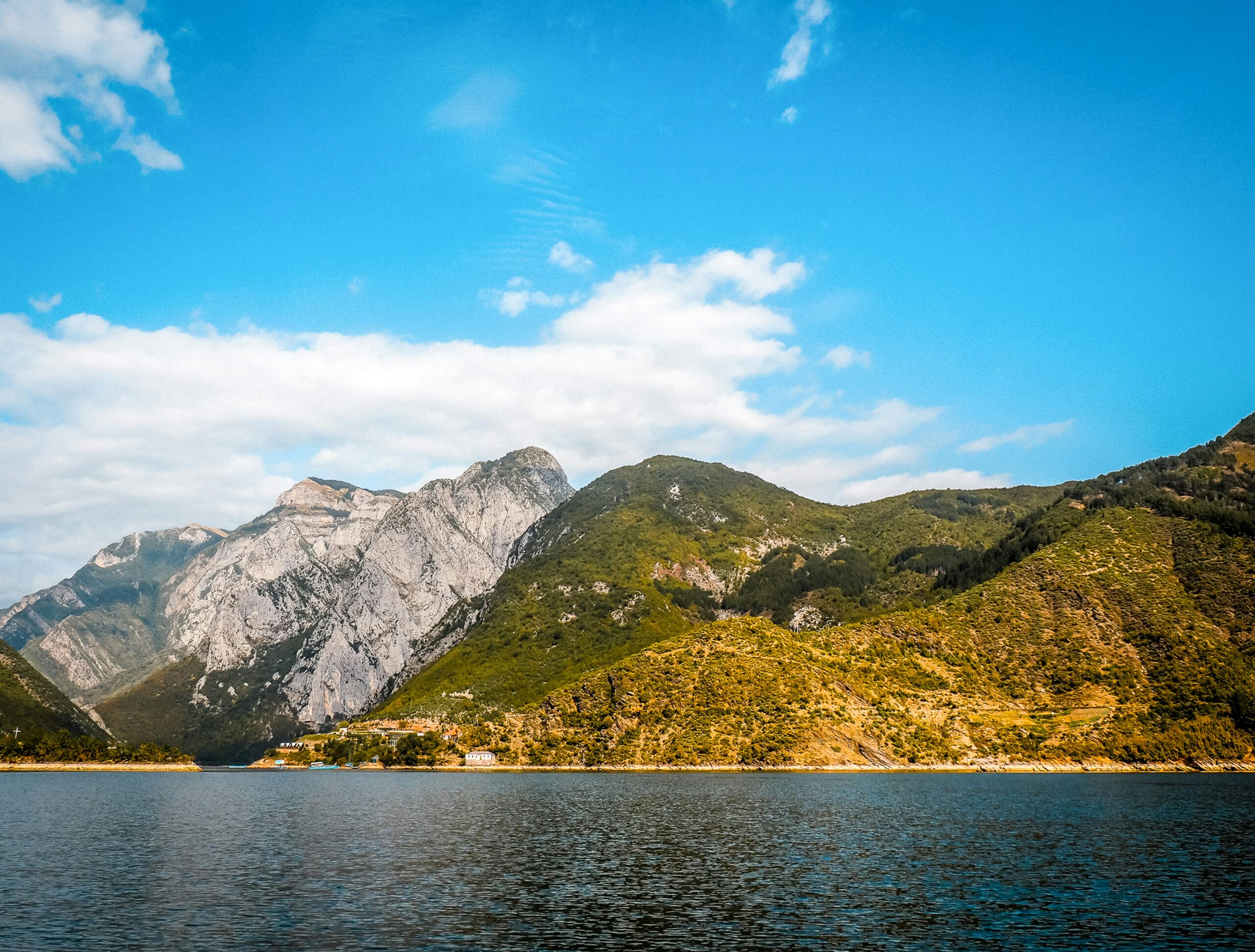 a body of water surrounded by mountains under a blue sky