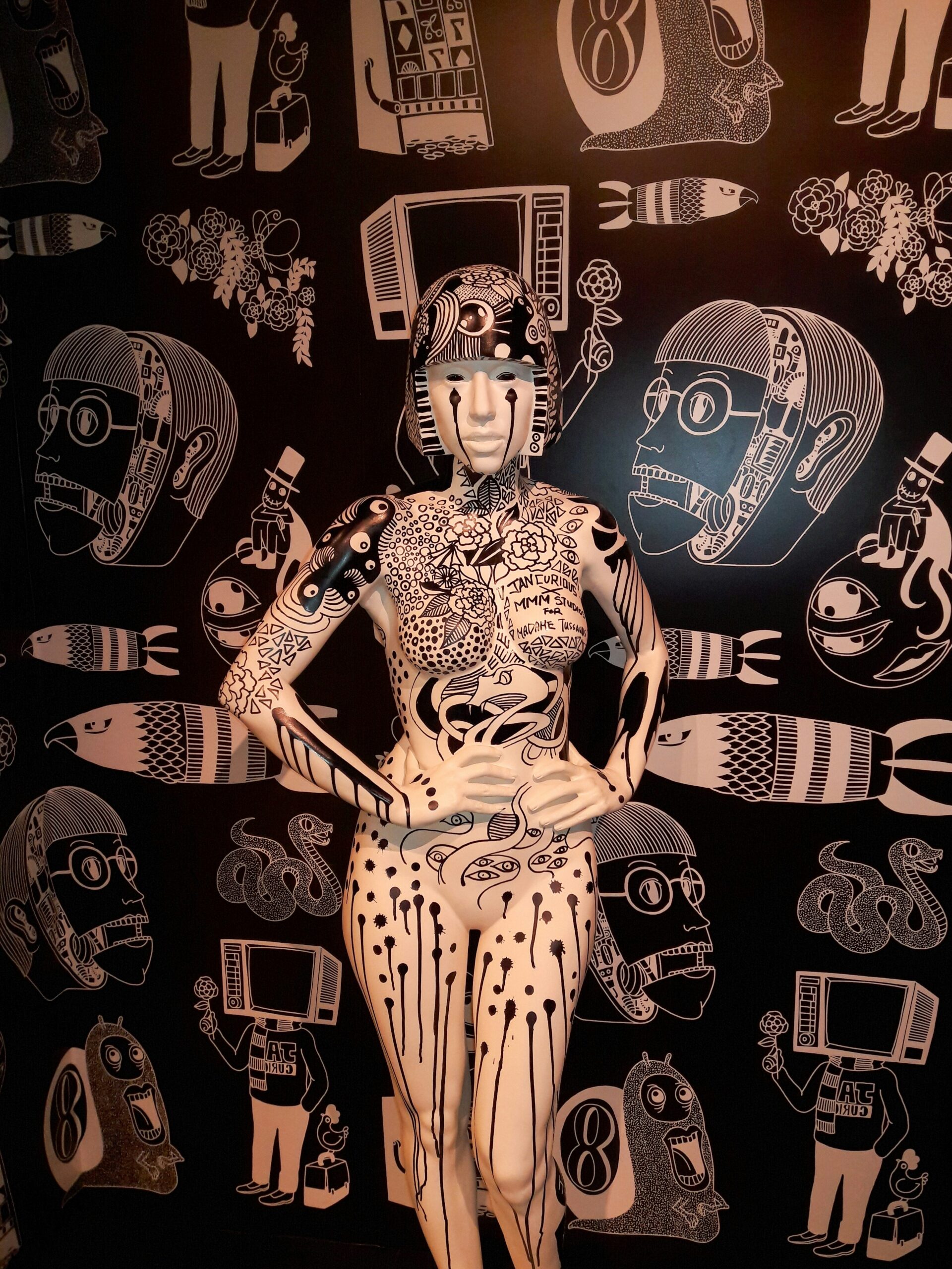 a mannequin is standing in front of a wall with many drawings on it