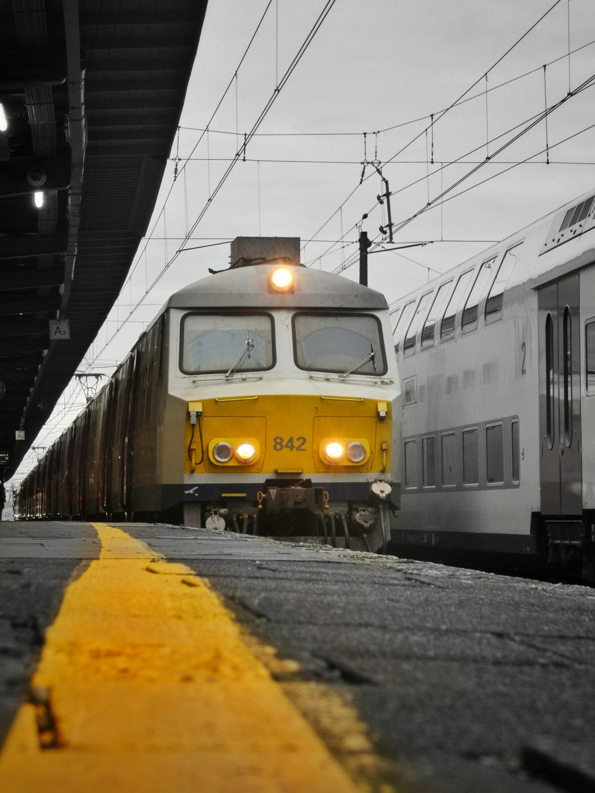 A yellow and white train pulling into a train station