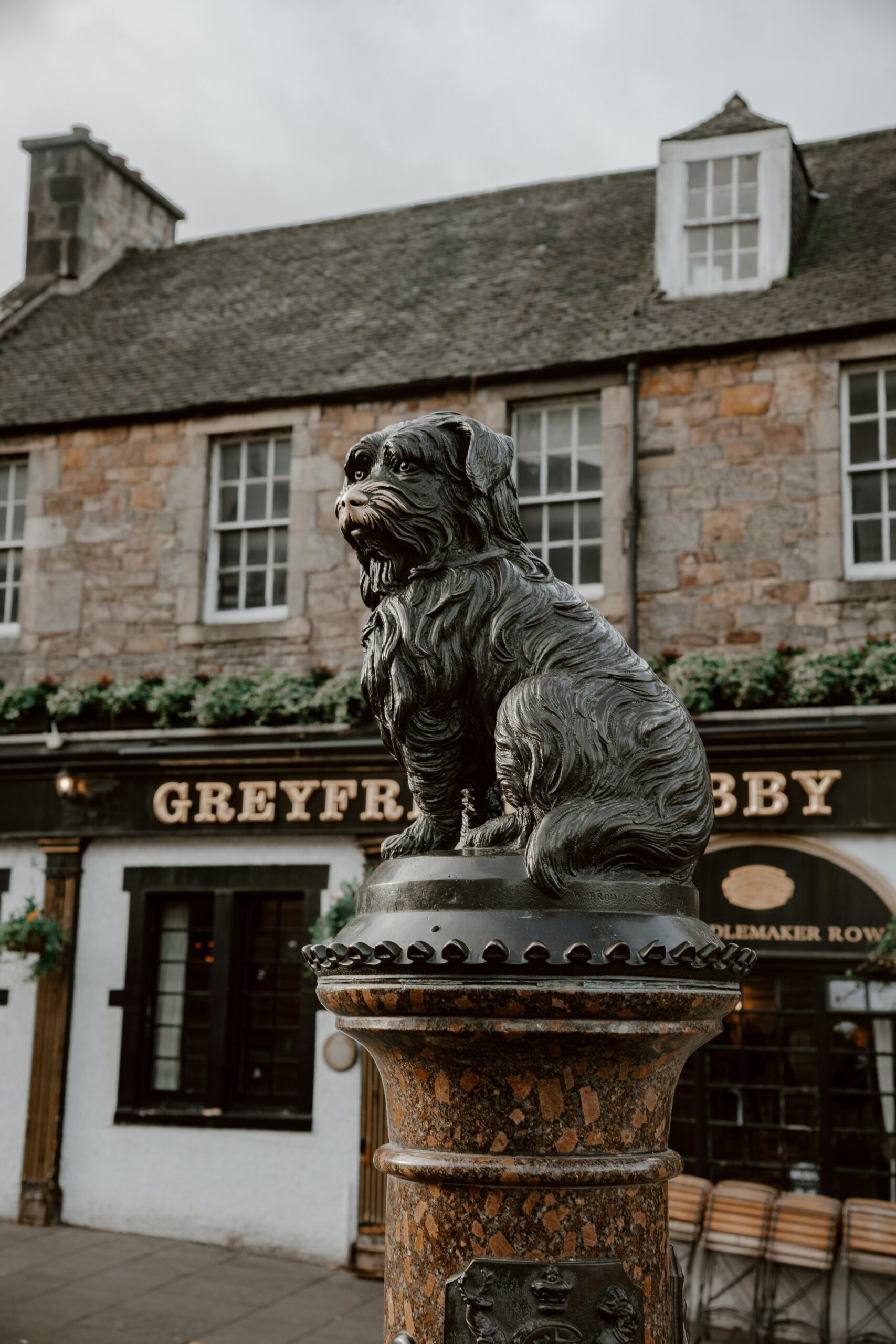 A statue of a dog on a pedestal in front of a building