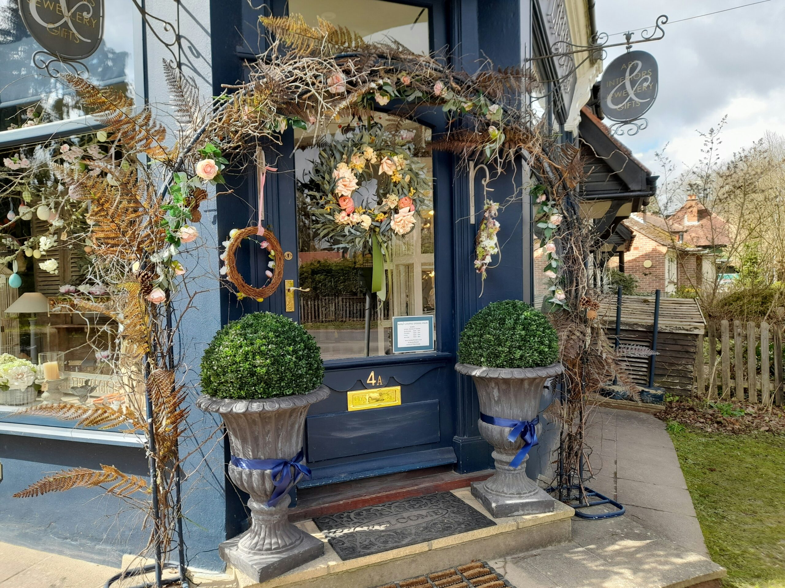 a blue store front with two planters and a clock