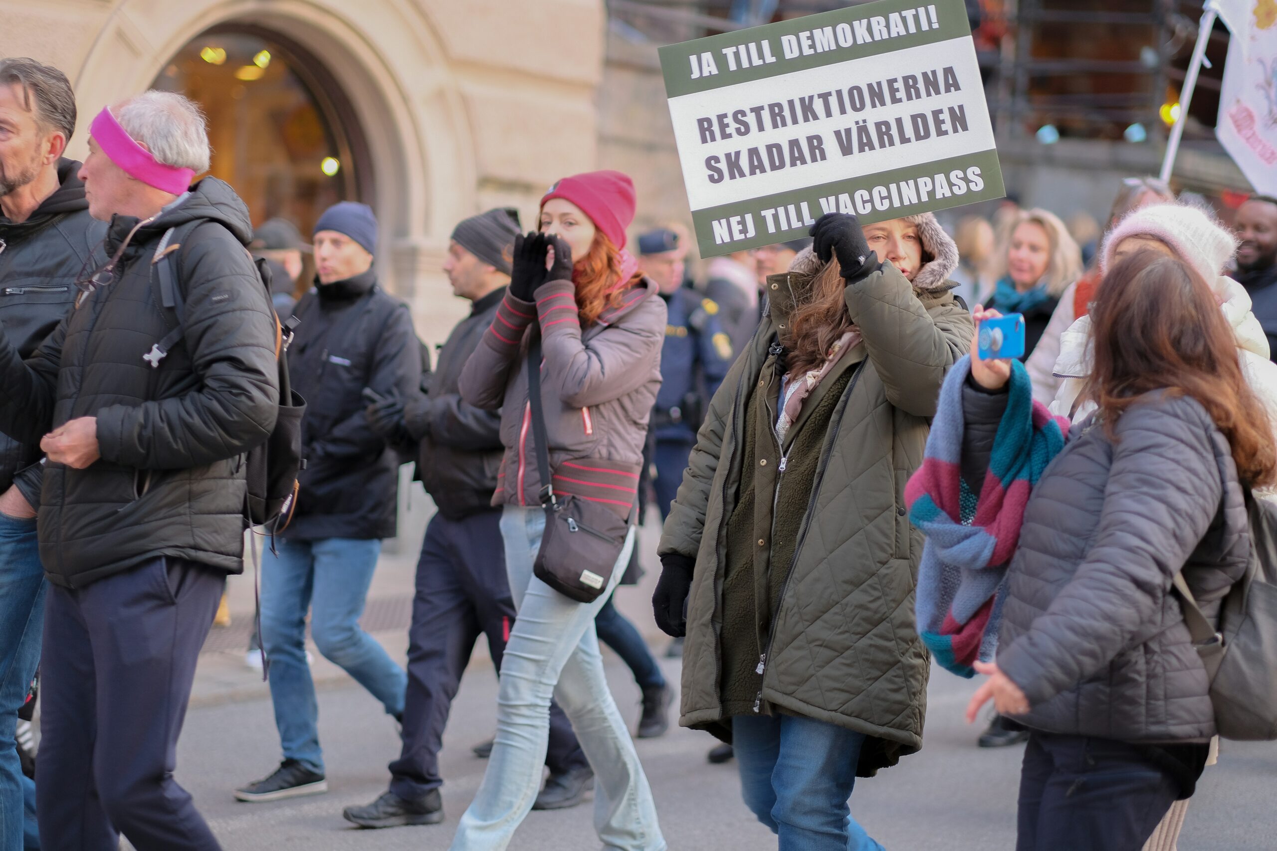 a group of people walking down a street holding signs