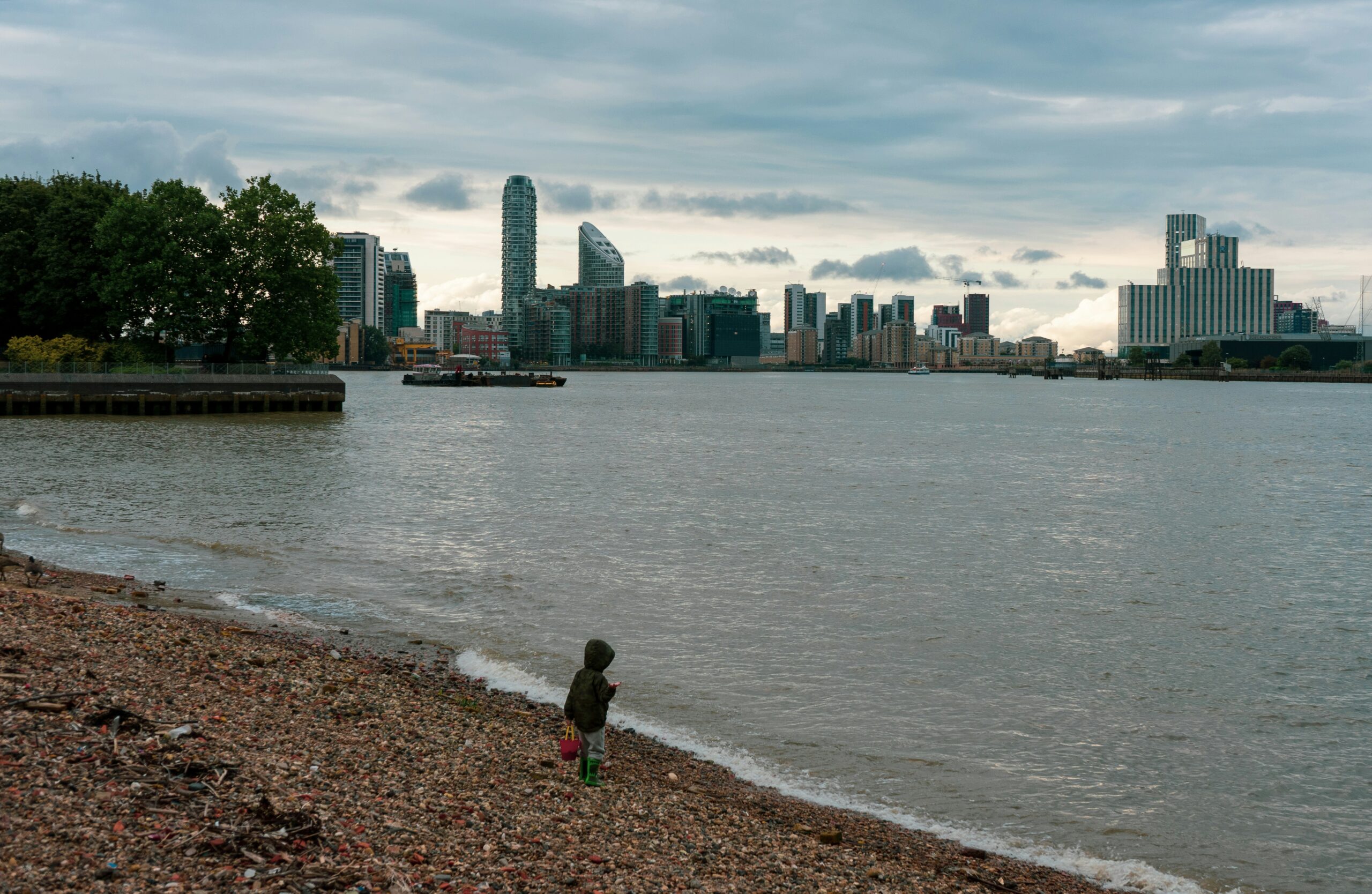 woman in black jacket walking on seashore during daytime